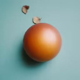 an orange colored, shiny egg with several brown leaves falling on it