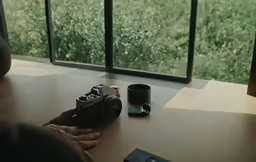 a person sitting at a table looking through a camera lens