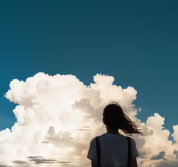 a woman is standing on a hilltop and is flying a kite