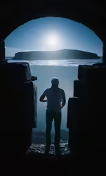 person in silhouette, looking out from cave near ocean
