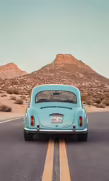 a turquoise car drives down an open road