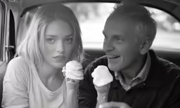 a man and woman in the back seat of a car eating ice cream