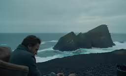 a man sitting next to a large body of water