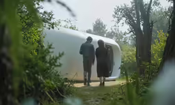 two people standing next to a white trailer that appears to be used for camping