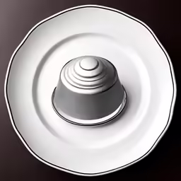 a small white object on a saucer on a dark table