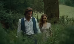 a man and woman walking in the forest