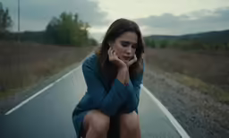 a girl on the phone sitting on the road