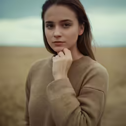 young woman with hands on chin looking out to the field