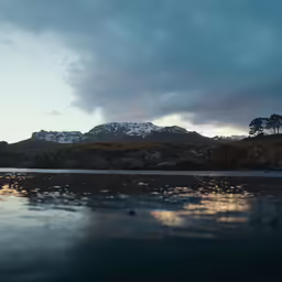 mountains and water are under a cloudy sky