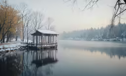 a gazebo in the water near some trees and snow