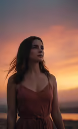 young woman standing in sunset looking up