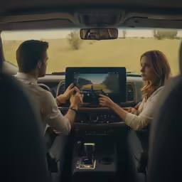 two people with tablet in the passenger seat of an automobile