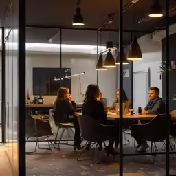 people are sitting at a table inside a meeting room