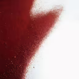 red liquid floating over white paper making a wave