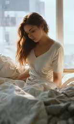 a woman laying in bed staring down