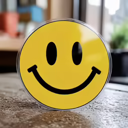 the yellow smiley face has black eyes and is resting on a counter