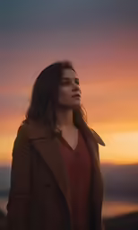 a woman in orange looking off into the distance