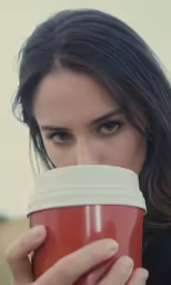 young woman with coffee cup in hand posing outdoors
