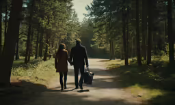 the man and woman are walking together down the dirt path
