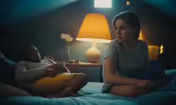 man and woman in dark bedroom with blue bed