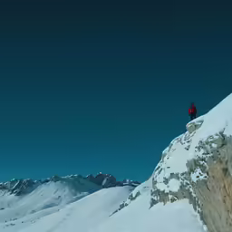 a person on skis standing on the side of a snow covered mountain