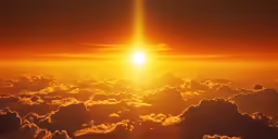 the sun peeking above clouds in the sky