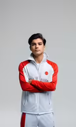 a young man in a white and red outfit standing with his arms crossed