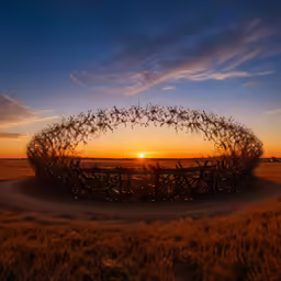 the sun sets behind a wire fence in a field