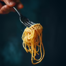 the fork is full of spaghetti as a person eats it