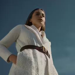 a women who is wearing a coat standing by the sky