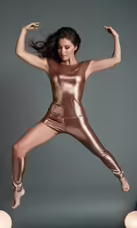 a woman in a gold and silver suit doing the splits