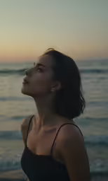 a woman standing near a body of water with the ocean in the background