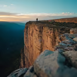 a person on top of the cliff during sunset