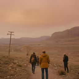 a group of people walking down a path near mountains