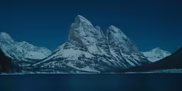 a snow covered mountain overlooks a body of water