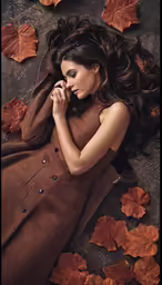a woman in a brown dress is laying on leaves