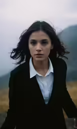 woman in a suit and white shirt in front of a mountain