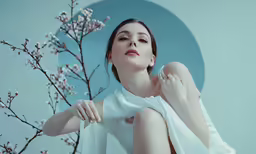 a woman in white dress next to tree with blossom