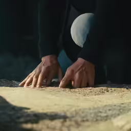 a man reaches over a desert like area while holding his hands