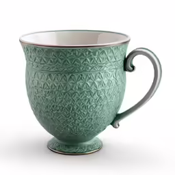 a green ceramic cup with an elaborate design