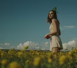 a woman in white dress walking through yellow flowers