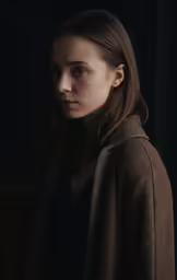 a woman standing in the dark holding onto something