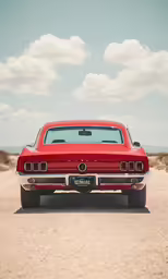 an old red classic car parked on the gravel
