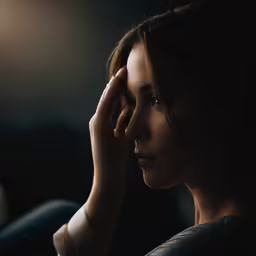 a woman holding her hands to her head while looking away from the camera