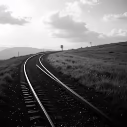 black and white picture of a train track running along the side of a hill
