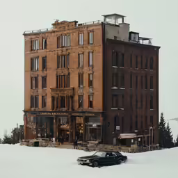 a snow covered car is parked outside a brown brick building