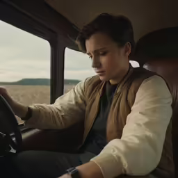 a young man is driving in a vehicle