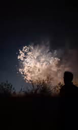a man standing in the grass next to a night sky