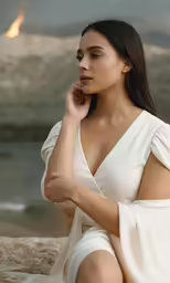 a woman is posing on a beach in her white gown