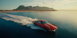a red classic car driving down the ocean